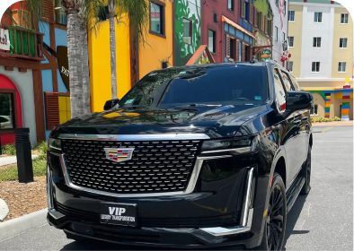 Black Cadillac SUV parked near colorful buildings.
