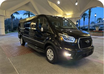 Black van parked under a lit canopy.