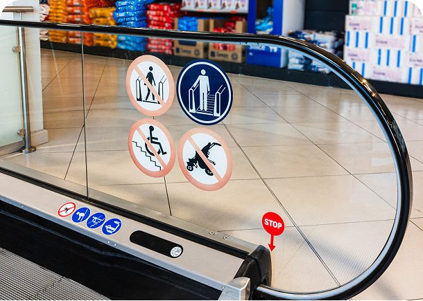 Escalator with safety warning signs displayed.