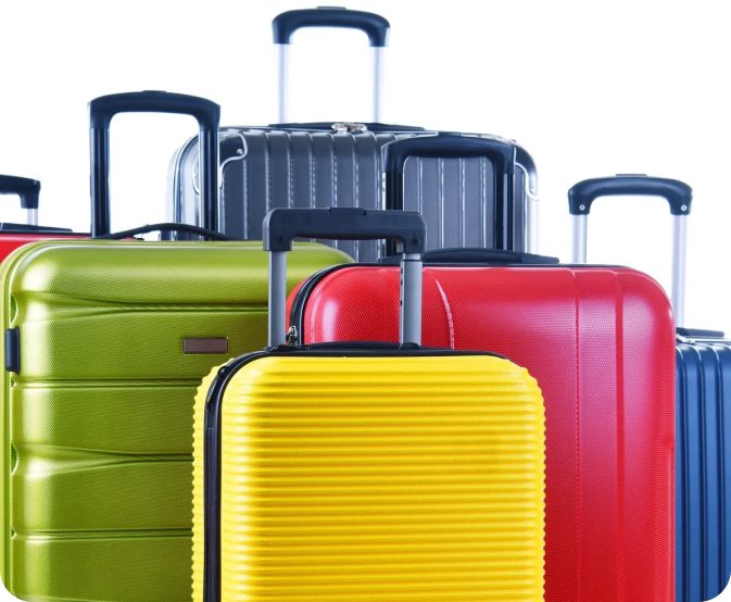 Colorful suitcases stacked against white background.
